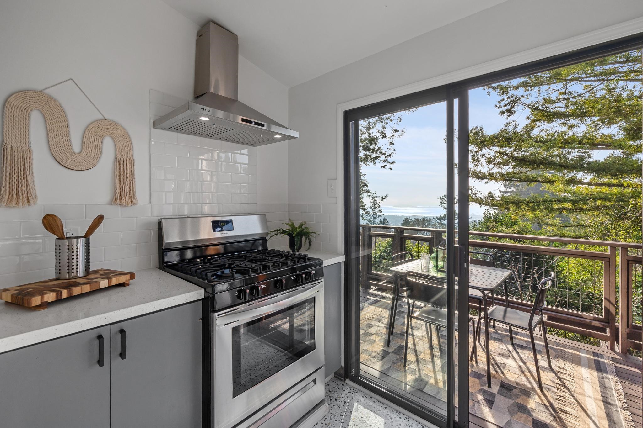 1024 Miller Avenue Berkeley, CA 94708 - Photo 23 of 60 Kitchen with stainless steel gas stove, wall chimney exhaust hood, dark aggregate flooring, gray cabinetry, and decorative backsplash