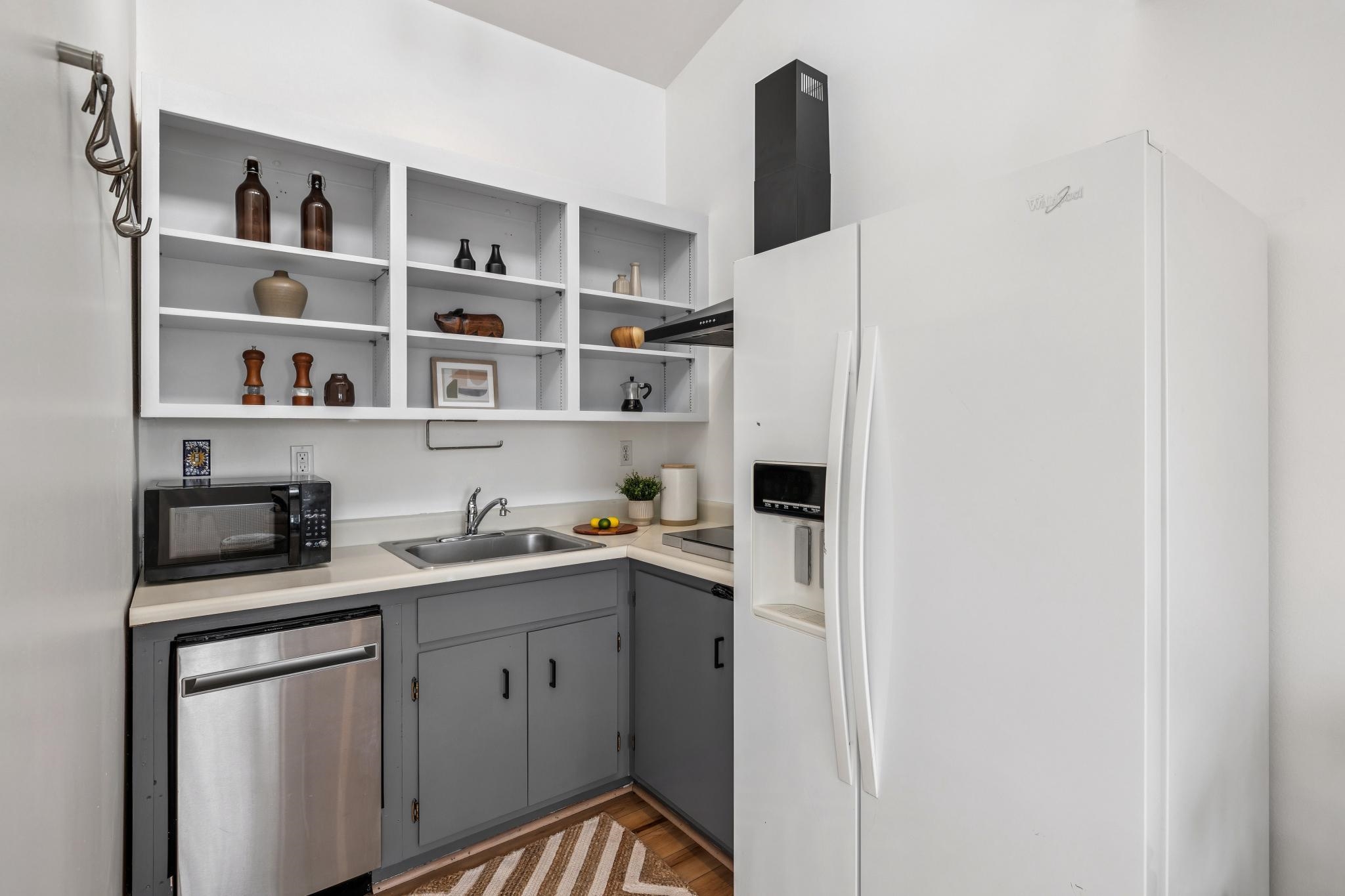 1024 Miller Avenue Berkeley, CA 94708 - Photo 56 of 60 Kitchen with gray cabinets, white refrigerator with ice dispenser, dishwasher, light countertops, and black microwave