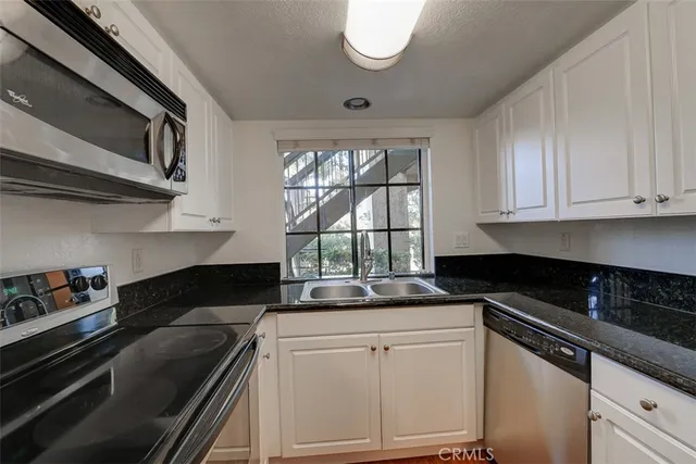 a kitchen with granite countertop a sink stove and cabinets