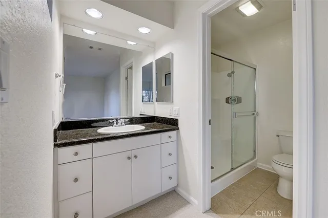 a bathroom with a granite countertop sink a toilet and shower