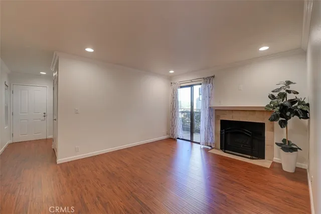 a view of an empty room with wooden floor fireplace and a window