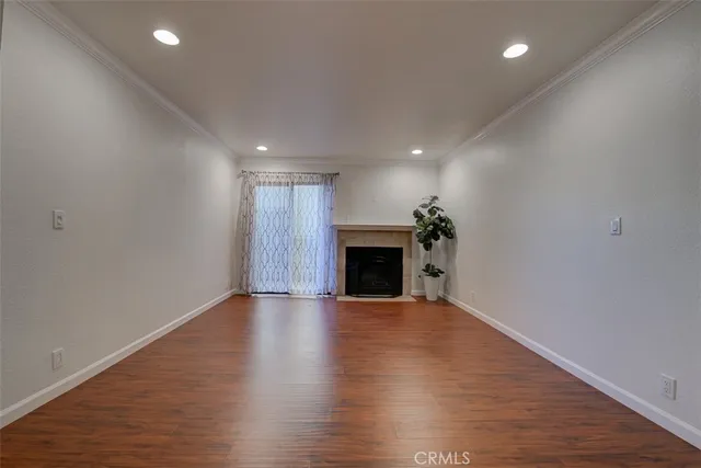 an empty room with wooden floor fireplace and chandelier