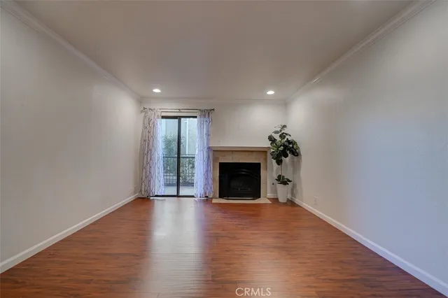 a view of an empty room with wooden floor fireplace and a window