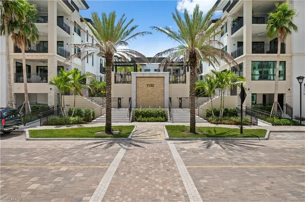 a view of a park with a apartment building and palm trees