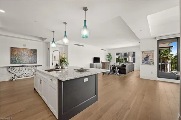 a large white kitchen with a large island oven a stove and a wooden floors