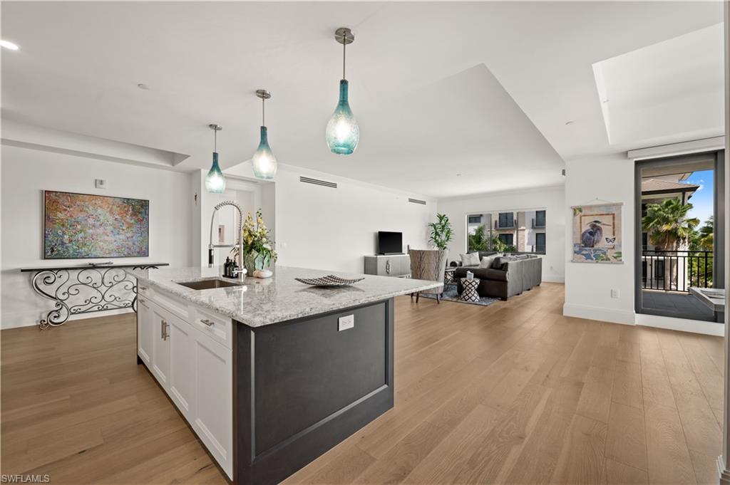 1130 3rd Avenue South, Unit 309 Naples, FL 34102 - Photo 4 of 29 a large white kitchen with a large island oven a stove and a wooden floors
