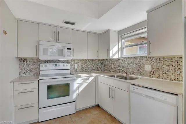 a kitchen with white cabinets stainless steel appliances and sink