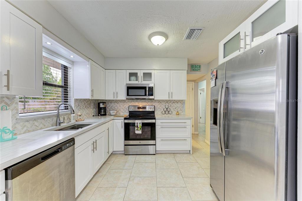 4424 87th St Court West Bradenton, FL 34210 - Photo 6 of 40 a kitchen with a sink cabinets stainless steel appliances and a window