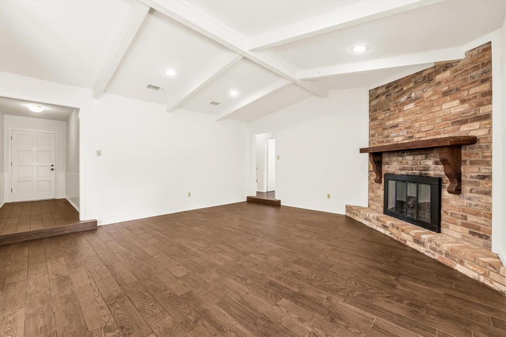 141 Travis Lane Hewitt, TX 76643 - Photo 5 of 31 Spacious living area featuring wood-finish flooring and a corner brick fireplace with a wood mantle