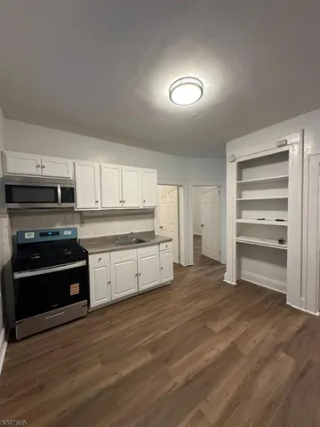 a kitchen with granite countertop a refrigerator stove and white cabinets