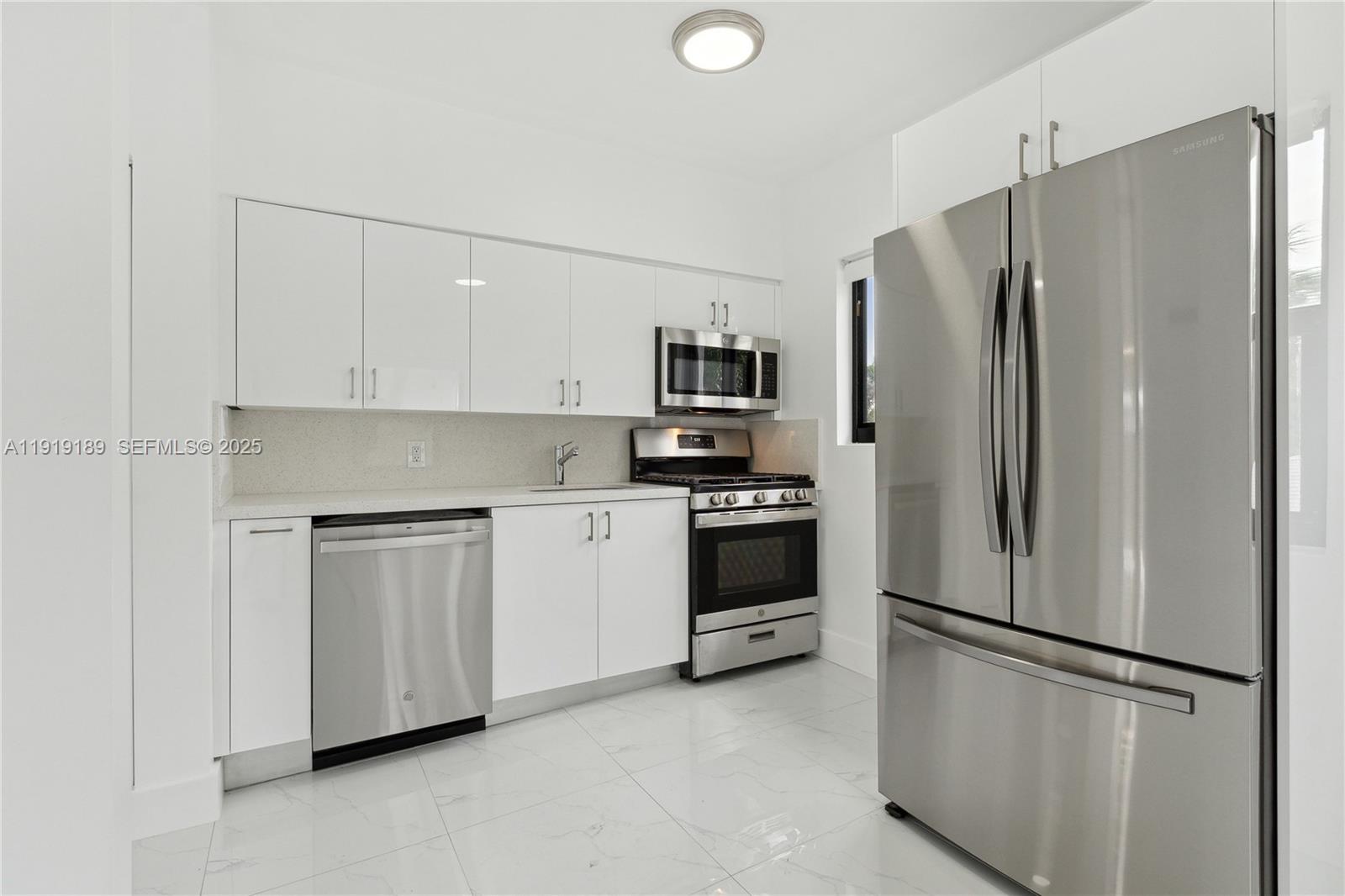 8010 Crespi Boulevard, Unit 4 Miami Beach, FL 33141 - Photo 3 of 16 a kitchen with stainless steel appliances white cabinets and a refrigerator