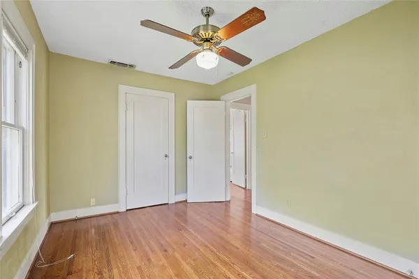 a view of an empty room with window and wooden floor
