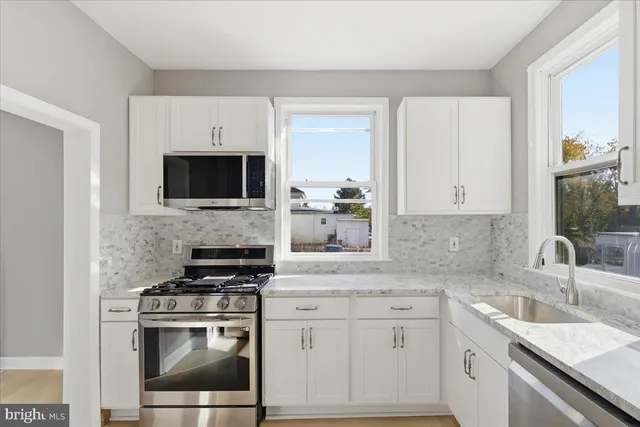 a kitchen with granite countertop a sink stove and microwave
