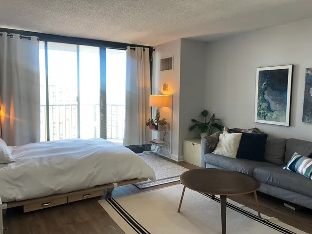 a bedroom with a bed couch and a large window