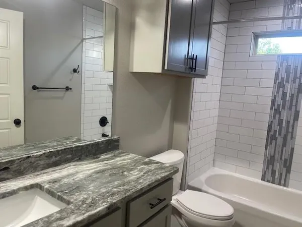 a bathroom with a granite countertop sink toilet and shower