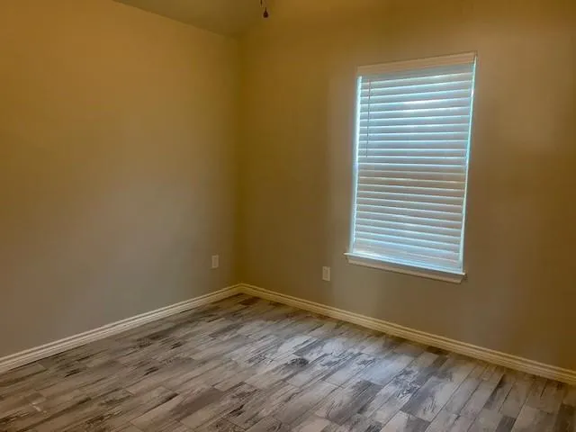 a view of an empty room with a window and wooden floor