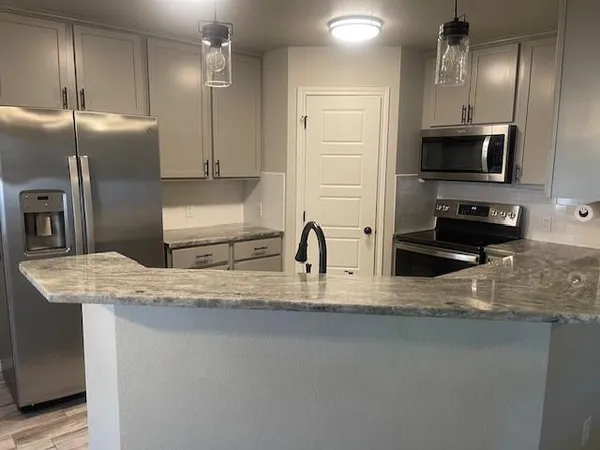 a kitchen with stainless steel appliances granite countertop a sink a refrigerator and a granite counter tops