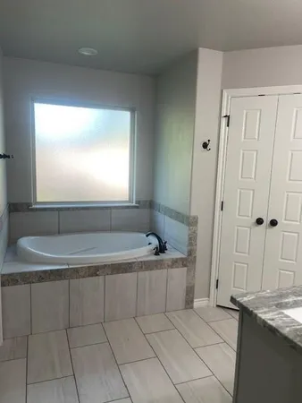 a spacious bathroom with a granite countertop tub sink and mirror