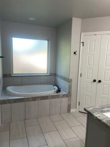 a spacious bathroom with a granite countertop tub sink and mirror