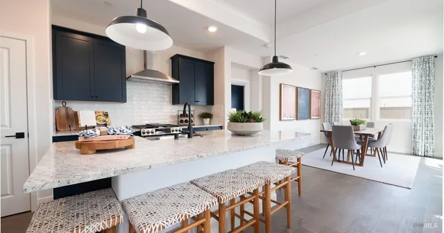 a kitchen with stainless steel appliances granite countertop a stove a sink a kitchen island a table and chairs