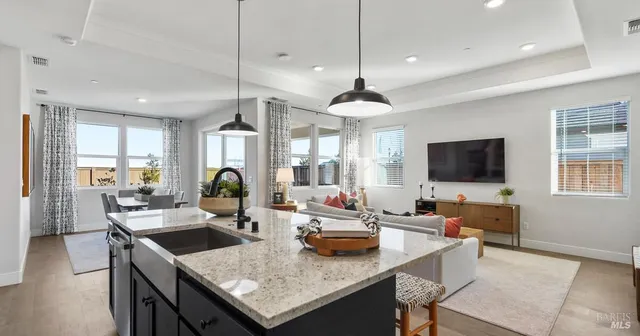 a living room with granite countertop couches a coffee table and a flat screen tv with kitchen view