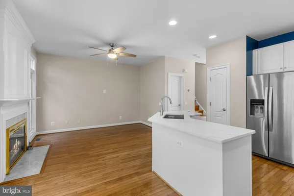 a kitchen with stainless steel appliances granite countertop a refrigerator a sink dishwasher a stove and white cabinets with wooden floor