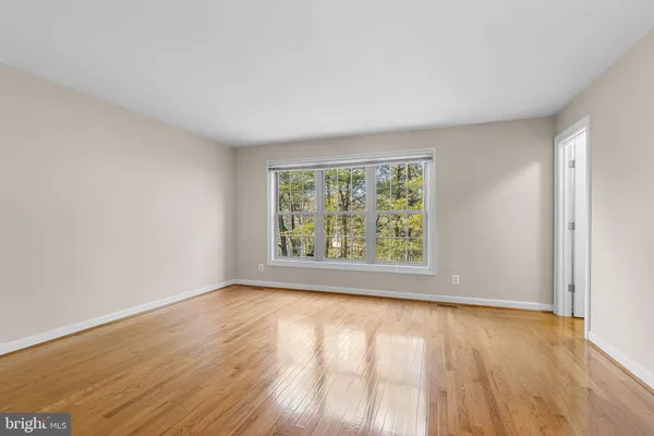 a view of an empty room with wooden floor and closet