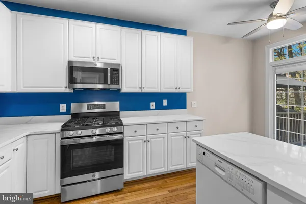 a kitchen with cabinets stainless steel appliances and a wooden floor