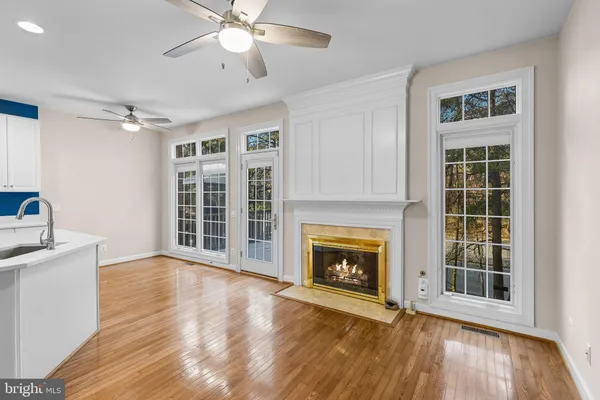a view of an empty room with wooden floor fireplace and a window