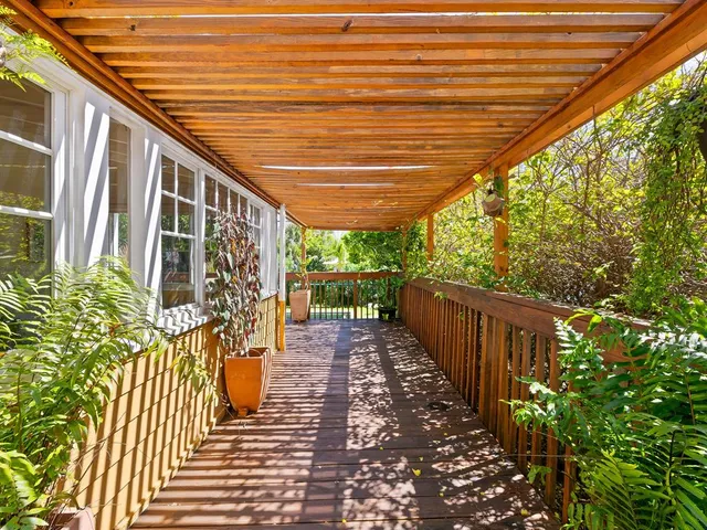 a view of a patio with table and chairs potted plants with wooden floor and fence