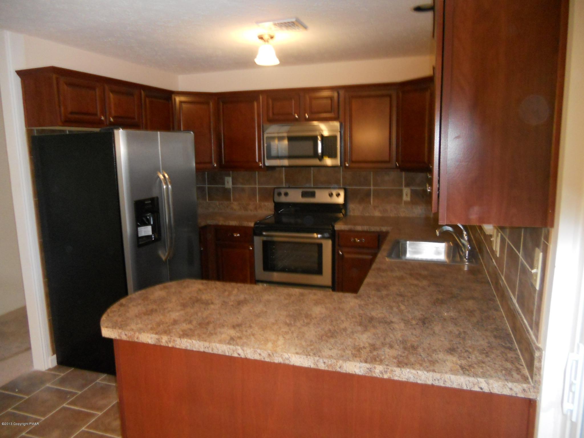 1123 Rhododendron Lane Pocono Summit, PA 18346 - Photo 4 of 10 a kitchen with stainless steel appliances granite countertop a refrigerator a stove and a sink