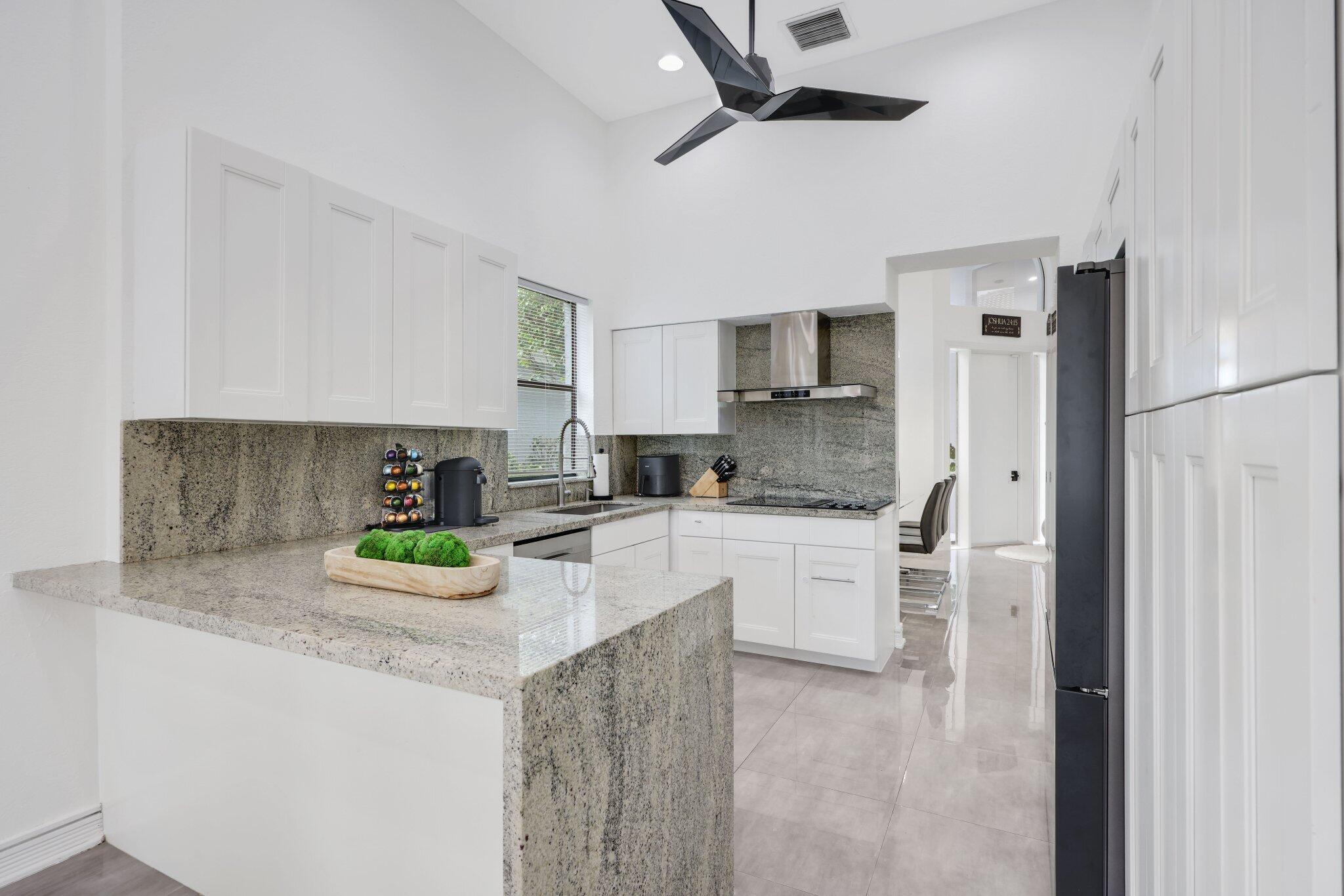10106 Spyglass Way Boca Raton, FL 33498 - Photo 15 of 44 a kitchen with a refrigerator a sink and white cabinets