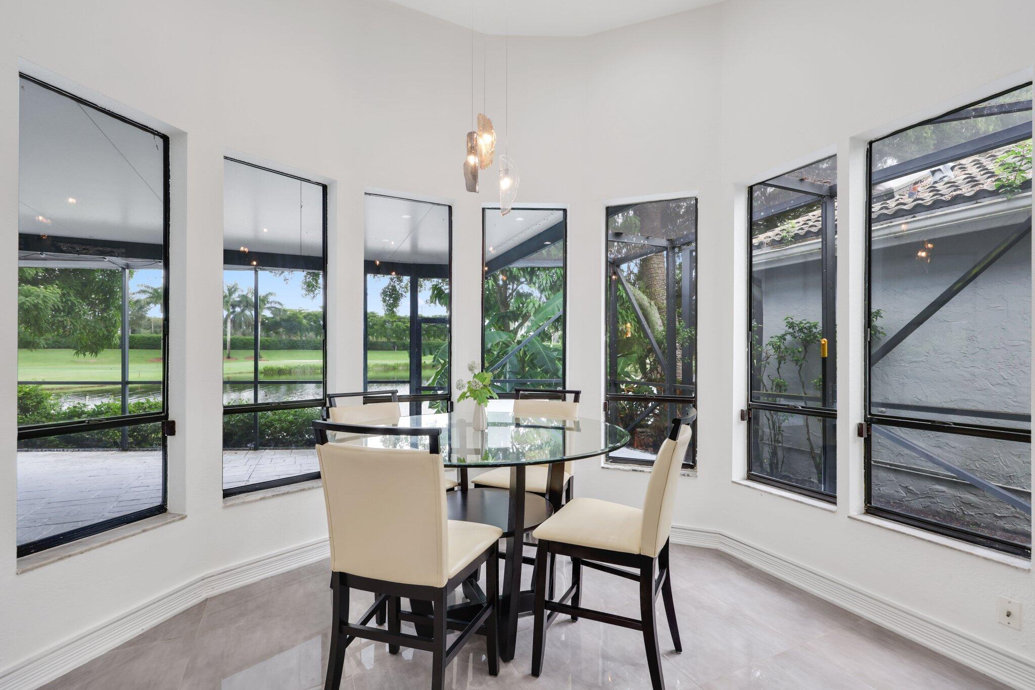 10106 Spyglass Way Boca Raton, FL 33498 - Photo 18 of 44 a dining room with furniture large windows and a chandelier