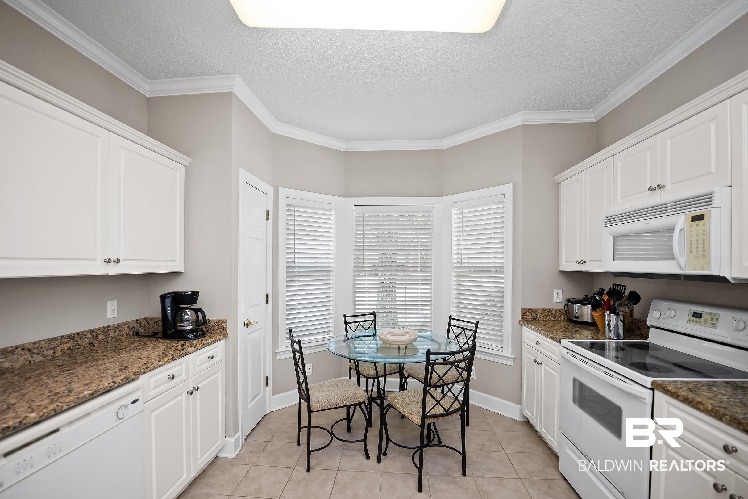 430 West Fort Morgan Road, Unit 704 Gulf Shores, AL 36542 - Photo 8 of 35 Kitchen featuring white cabinetry, speckled countertops, tile flooring, and integrated appliances