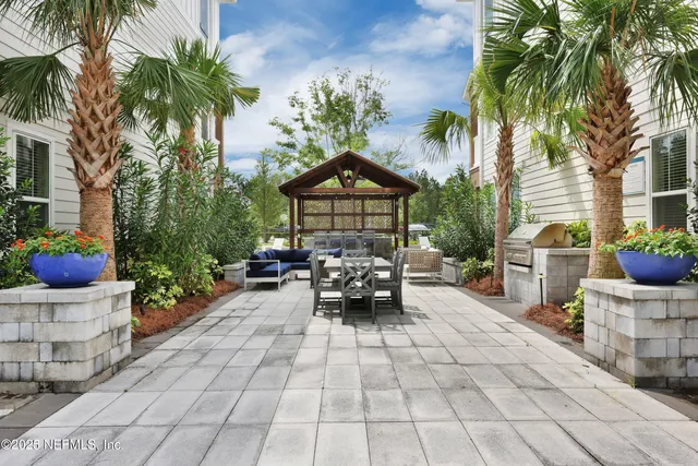 a view of a patio with dining table and chairs potted plants and palm trees