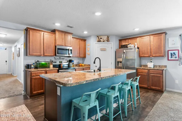 a kitchen with stainless steel appliances granite countertop a stove a sink a microwave a refrigerator and cabinets