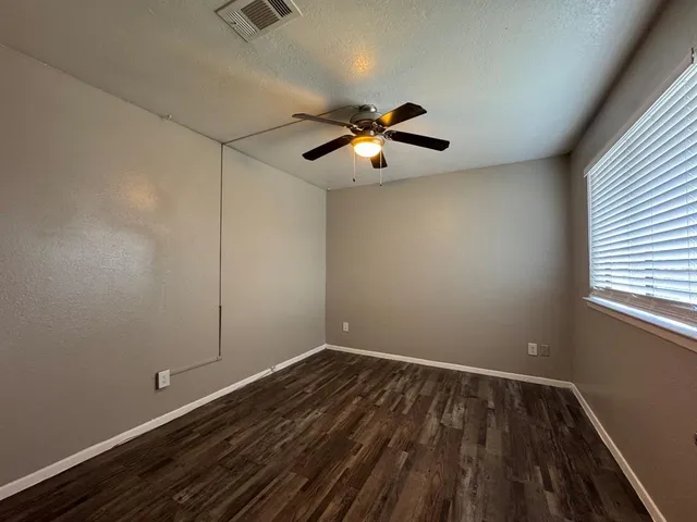 a view of room with hardwood floor and a ceiling fan