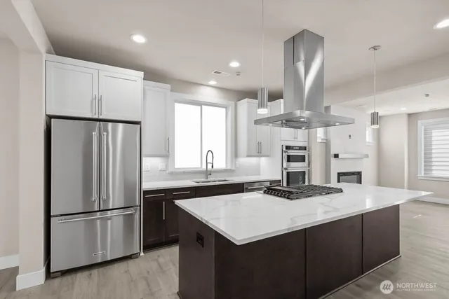 a kitchen with kitchen island stainless steel appliances a sink and a refrigerator