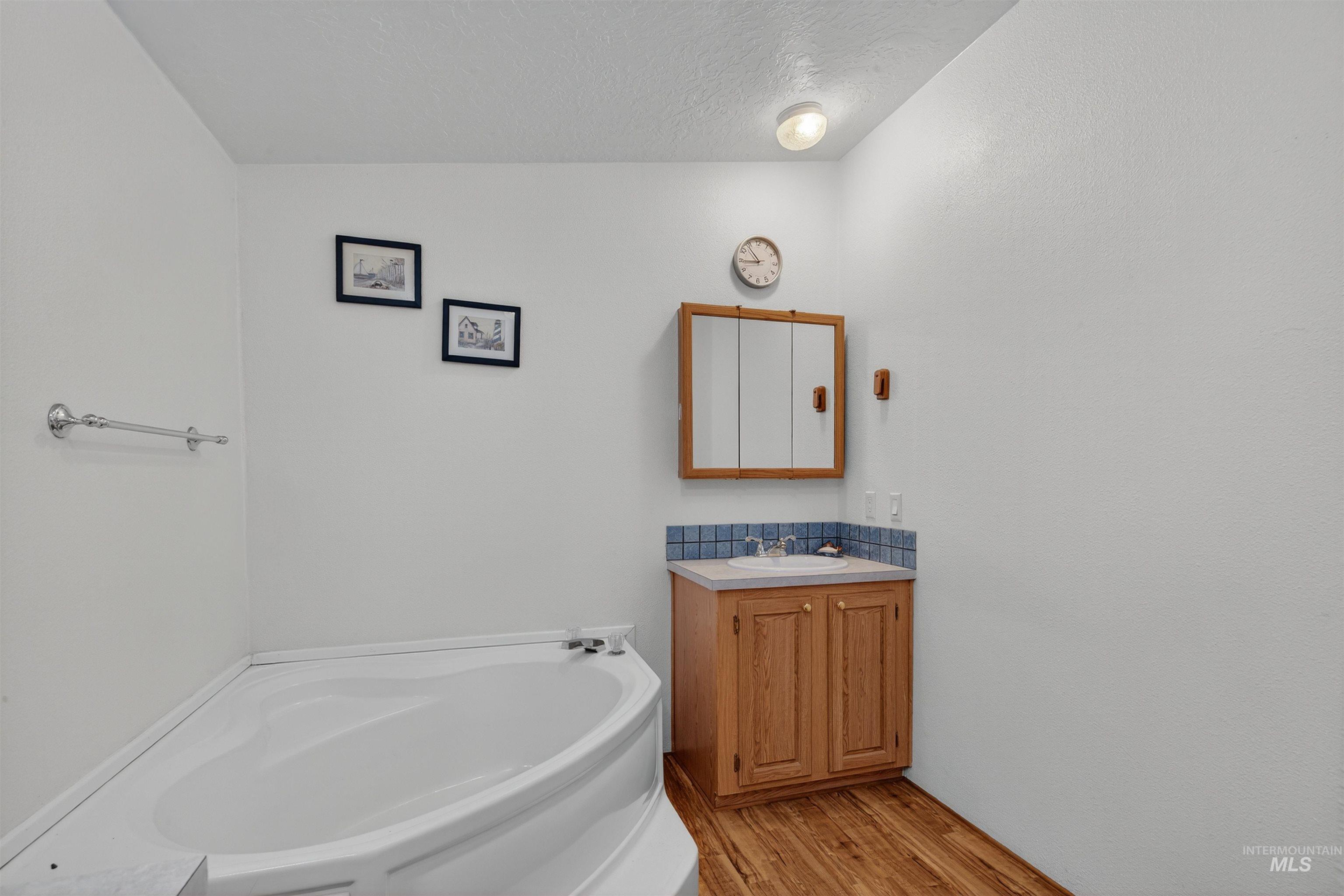 4151 Highway 13 Stites, ID 83552 - Photo 24 of 50 Bathroom featuring a garden tub, light wood-style floors, vanity, and a textured ceiling
