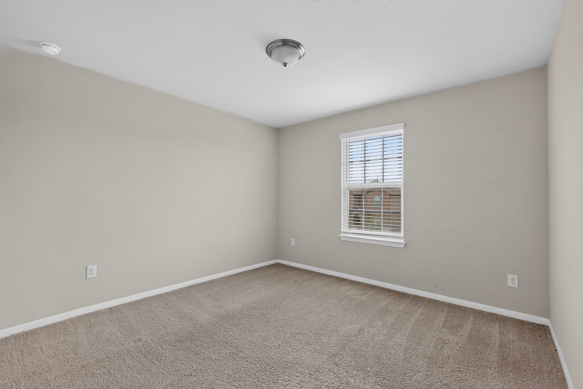 6920 Ranchito Drive Austin, TX 78744 - Photo 16 of 19 A well-lit room with plush carpeting offers a cozy and versatile living space.