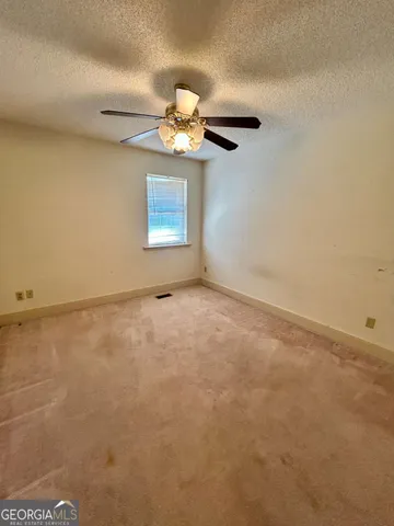 an empty room with a chandelier fan and windows