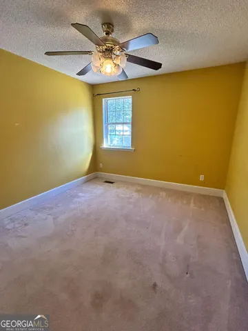 an empty room with a window and chandelier fan