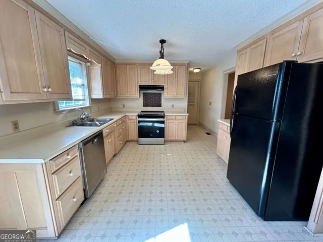 a kitchen with granite countertop a refrigerator stove and sink