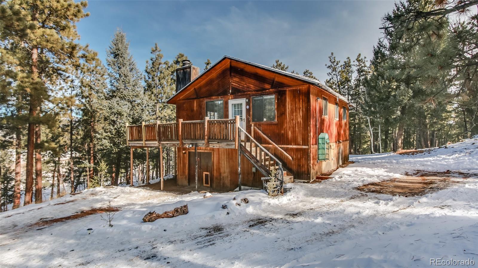 156 Ranchettes Road Bailey, CO 80421 - Photo 3 of 23 a view of a wooden house with large trees and wooden fence