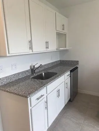 a kitchen with granite countertop white cabinets and sink