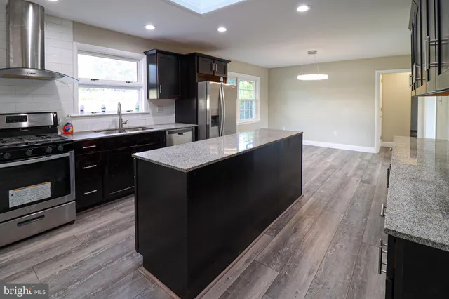 a kitchen with stainless steel appliances granite countertop a stove a sink and a refrigerator