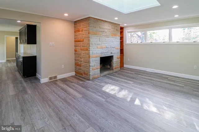 an empty room with wooden floor a fireplace and windows