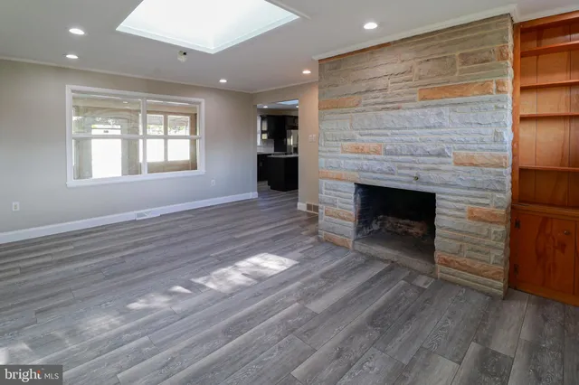 an empty room with wooden floor fireplace and windows