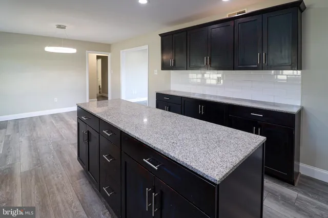 a kitchen with kitchen island granite countertop wooden cabinets a sink and dishwasher