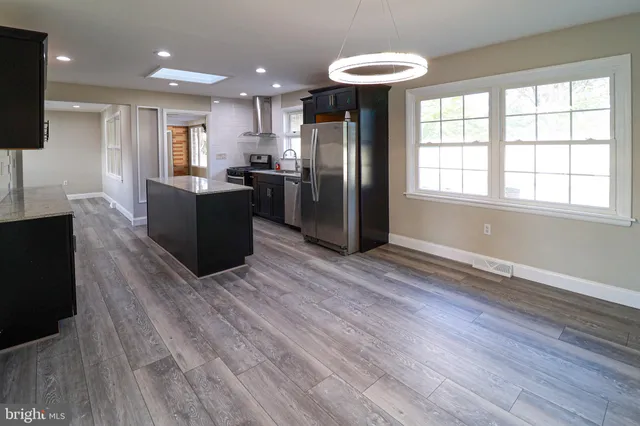 a view of kitchen with stainless steel appliances granite countertop a refrigerator a sink dishwasher a stove and a dining table with wooden floor